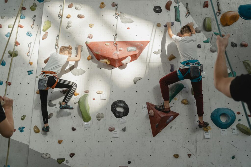 Bild von zwei Kindern die an einer Boulderwand h9ochklettern