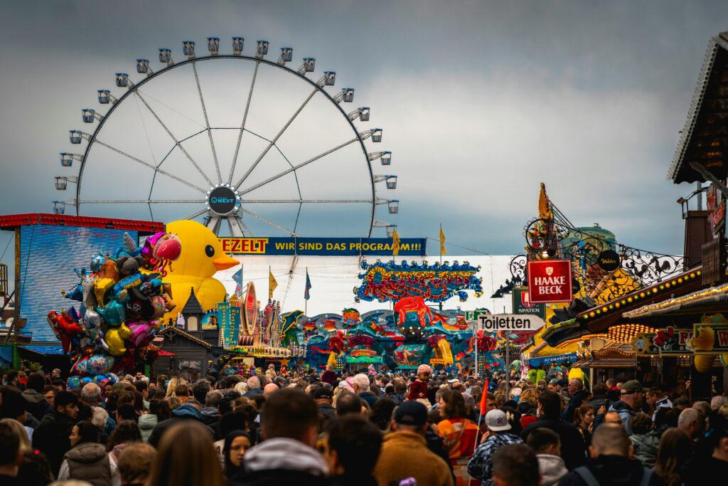 Menschenmenge auf dem Rummel Mit Riesenrad im Hintergrund.