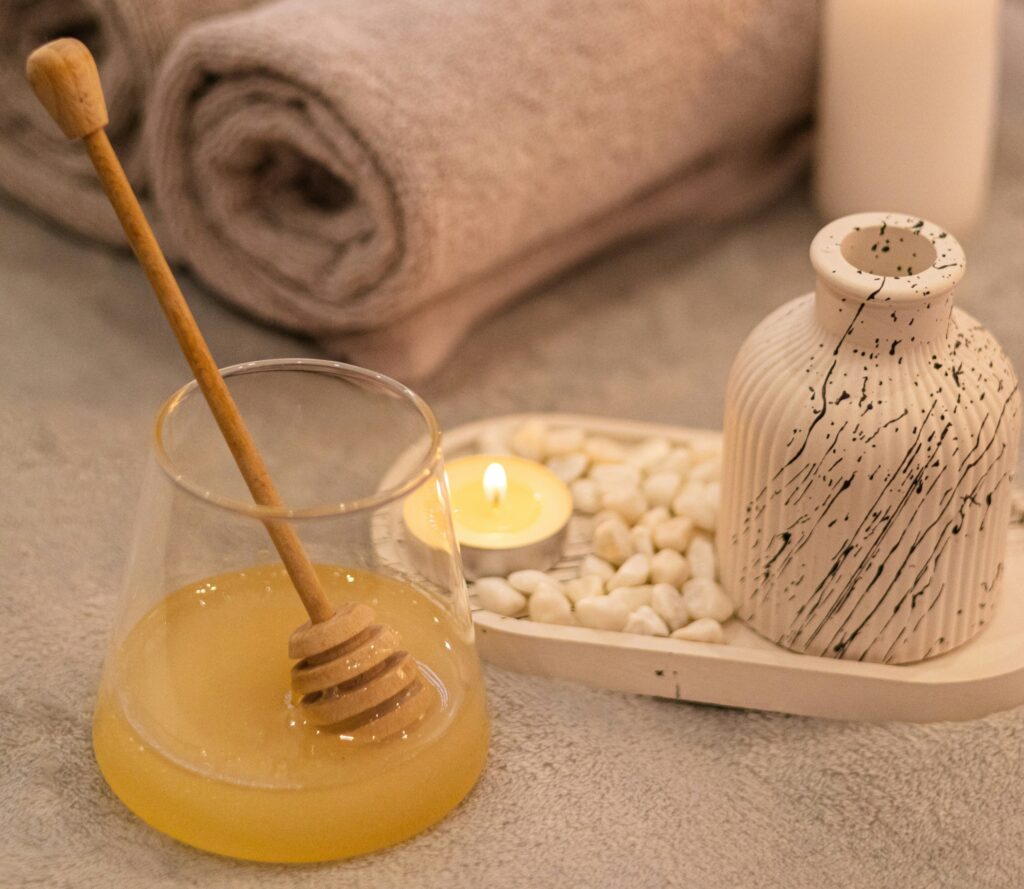 Honig, eine brennende Kerze und elegant gerollte Handtücher.