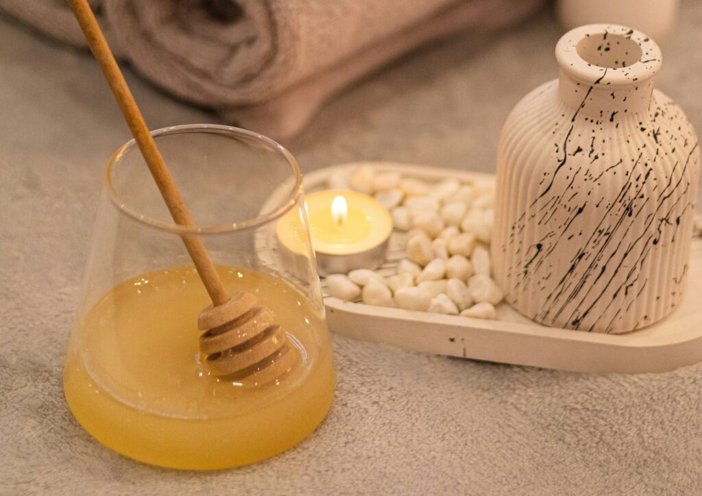 Honig, eine brennende Kerze und elegant gerollte Handtücher.