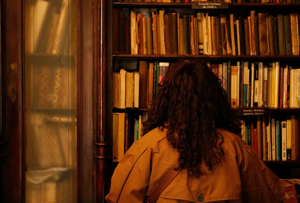 Eine Frau steht vor einem hohen, antiken Bücherregal.