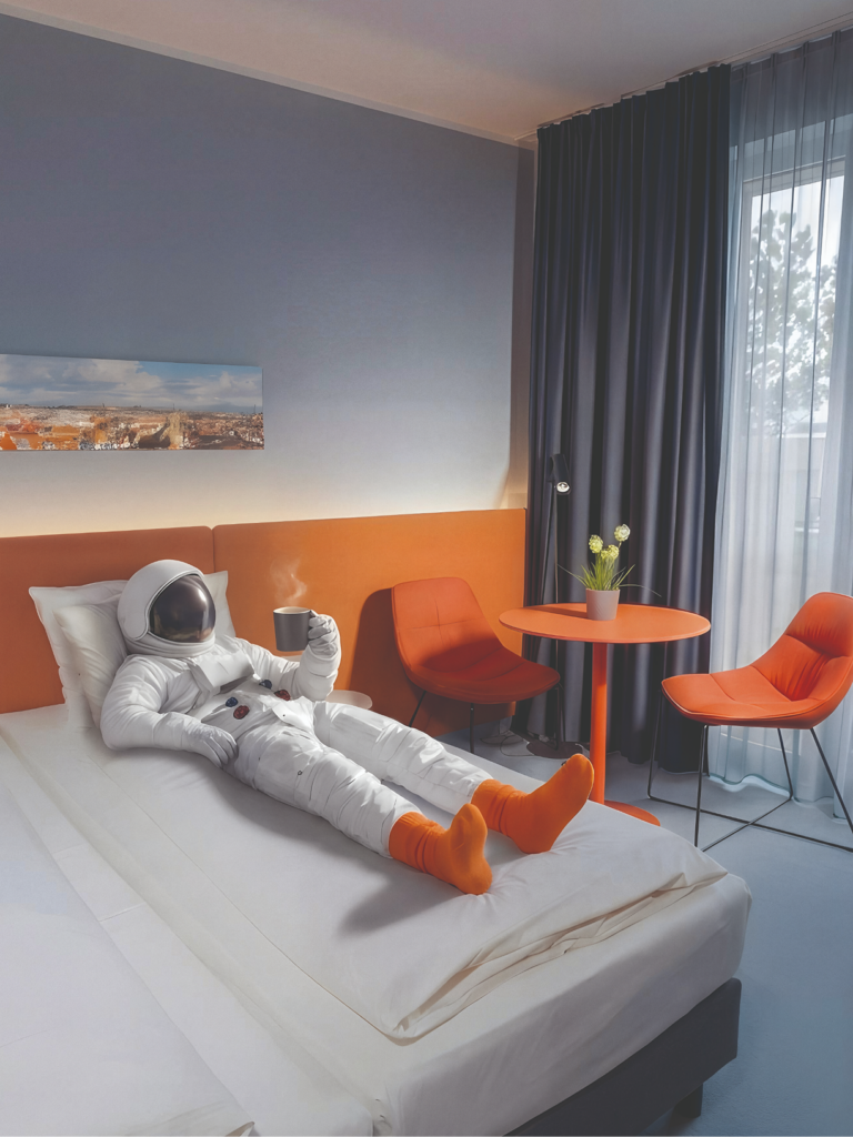 Astronaut im Hotelzimmer wie er im Bett liegt.